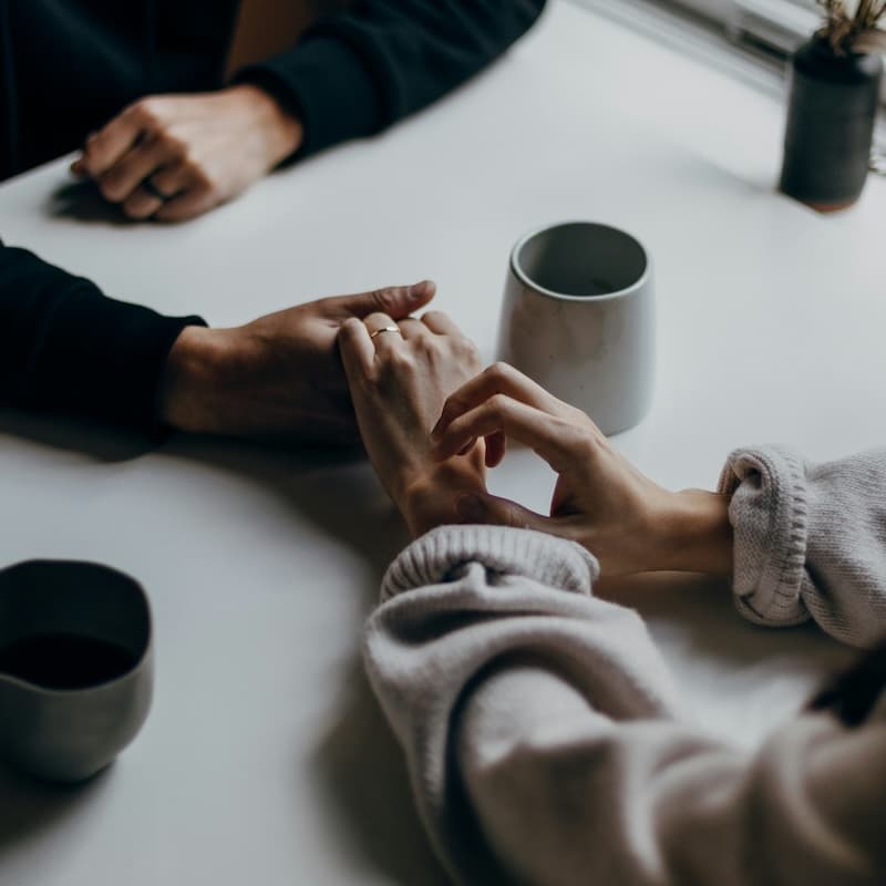 Couple holding hands during an online couples therapy session.
